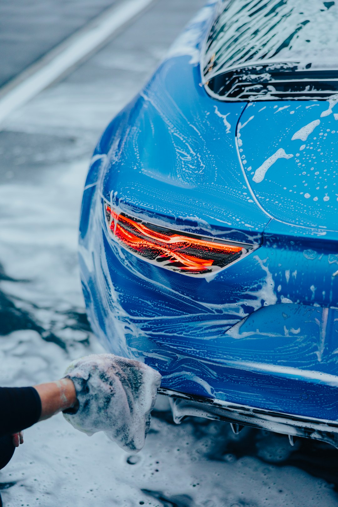 a-person-washing-a-blue-car-with-a-rag-a9nu9-pvjiw